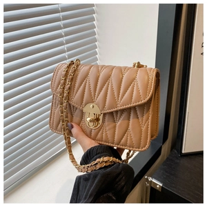 Detail of camel quilted crossbody bag featuring wave patterns and gold chain strap