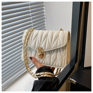 Close-up of white quilted leather texture and gold metal turn-lock on the small square bag