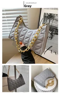 Detail view of a grey quilted shoulder bag with luxurious bold gold chain handle