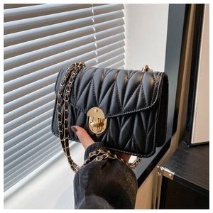 Close-up of black quilted crossbody bag with golden clasp and leather chain strap