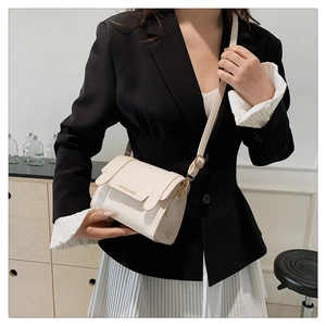 Close-up of cream crossbody square bag with gold Fashion & Bags lettering on shoulder