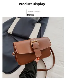 Detail view of a vintage brown leather crossbody bag with a large golden square buckle