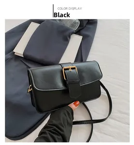 Detail of a black leather rectangular crossbody bag featuring a large gold square buckle
