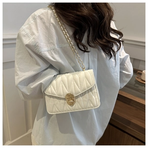 Sac bandoulière blanc matelassé avec chaîne dorée porté par un mannequin