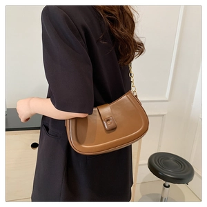 Detail showing the brown faux leather crescent bag with a decorative gold chain strap