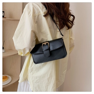 Detail of a black leather rectangular crossbody bag featuring a gold square metal clasp