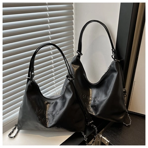 Détail du sac hobo en cuir noir avec logo MUDOU COLO DESING embossé et bandoulière