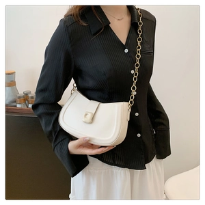 Detail of white half-moon shoulder bag with thick gold chain strap and square buckle