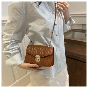 Détail d'un sac à chaîne matelassé marron avec coutures en V et fermoir rotatif doré