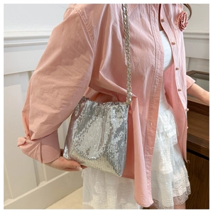 Detailed close-up of shiny silver sequin bucket bag with elegant metal chain strap