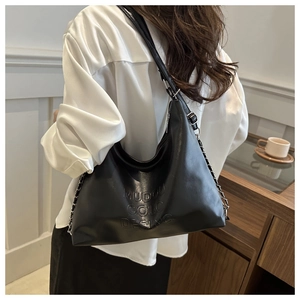 Détail du grand sac hobo noir en similicuir vernis avec logo embossé et bandoulière
