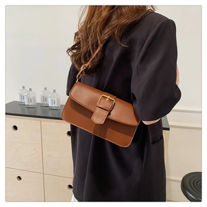 Brown vintage PU leather crossbody bag with a bronze buckle shown in a lifestyle setting