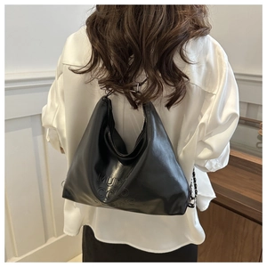 Détail d'un sac cabas en similicuir noir avec motif embossé porté par un mannequin