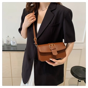 Sac bandoulière en cuir marron avec rabat et grande boucle porté sur tenue décontractée