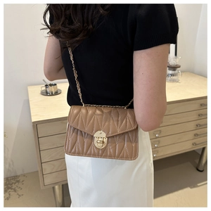 Sac bandoulière matelassé chameau avec chaîne dorée porté par un mannequin chic