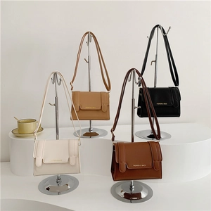 Stylish square leather shoulder bags in four colors with gold lettering on a display stand