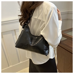 Gros plan du sac noir avec lettres embossées et détail de chaîne en métal élégant