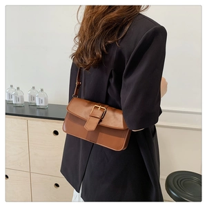 Détail d'un sac sous les bras en cuir marron avec design vintage carré et boucle dorée