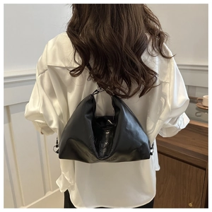 Détail du sac plissé noir montrant la texture du cuir brillant et le gaufrage de lettres
