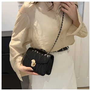 Détail du sac matelassé noir avec serrure rotative dorée et texture plissée brillante