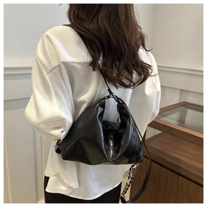 Détail du sac sous l'aisselle en similicuir plissé noir avec chaîne et logo embossé
