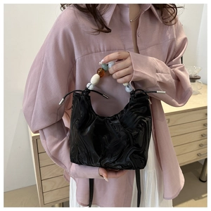 Close-up of black bucket bag featuring unique agate bead handle and drawstring closure