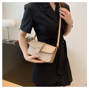 Gros plan détaillé d'un sac bandoulière en cuir beige avec boucle dorée élégante