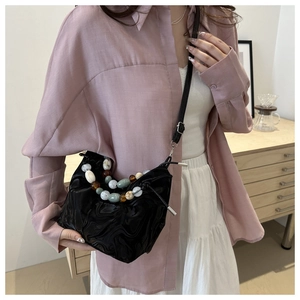 Detail of black pleated tote bag with colorful beaded handle and slim shoulder strap