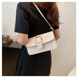 Détail du sac à bandoulière crème avec boucle dorée porté par un mannequin pour taille