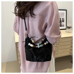 Detail of black marble cloud bag with colorful beads and drawstring closure on a model