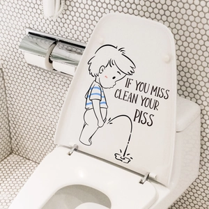 Detail view of cartoon boy toilet sticker with humorous text on a white bathroom lid