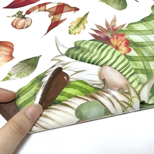 Close-up of easy-to-peel watercolor gnome and pumpkin fall window stickers being applied