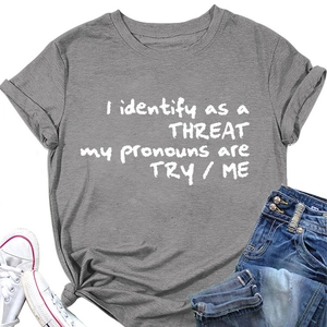Détail du t-shirt gris avec le slogan I identify as a THREAT et texture de maille douce