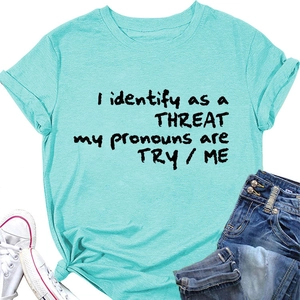 T-shirt vert avec slogan 'I identify as a THREAT' disposé à plat avec short en jean