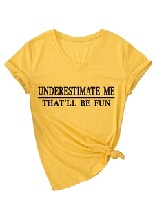 Détail d'un t-shirt jaune col en V avec manches retroussées et slogan UNDERESTIMATE ME