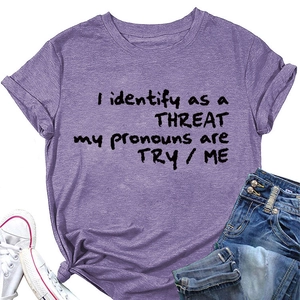 Détail d'un t-shirt violet avec ourlet noué et le slogan I identify as a threat