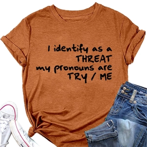 Détail du t-shirt orange rouille avec le slogan I identify as a THREAT imprimé en noir