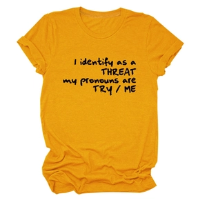 Détail du t-shirt jaune moutarde avec le slogan I identify as a threat en noir