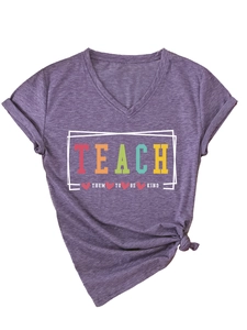 Detail of V-neck purple t-shirt featuring colorful Teach Them To Be Kind print and knot hem