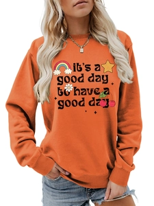 Détail d'un sweat orange avec motifs arc-en-ciel et typographie colorée de près