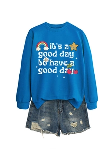 Sweat bleu avec motifs colorés et short en jean déchiré posés à plat sur fond blanc