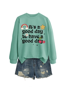 Mise à plat du sweat vert menthe avec imprimé arc-en-ciel et mini-short en jean déchiré