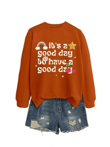 Détail du sweat orange avec imprimé arc-en-ciel et short en jean bleu délavé