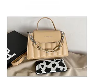 Detail of vertical quilted faux leather bag with chunky cream chain and top handle