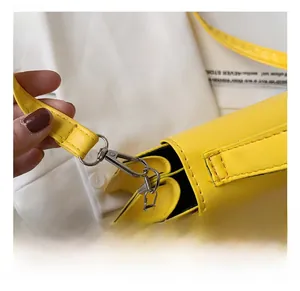 Detailed macro view of yellow leather bag with silver metal hook and strap connection