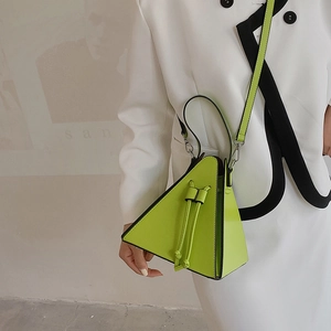 Sac à main triangulaire vert citron chic avec bandoulière sur un costume moderne