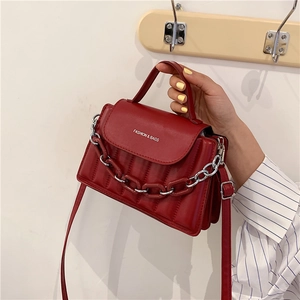 Detail of red quilted leather handbag with silver chain and white fashion branding text