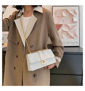 Detail of white crocodile pattern shoulder bag with gold chain and metal lock