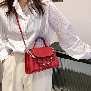 Detail of red quilted crossbody bag with dual-tone metal and acrylic chain strap