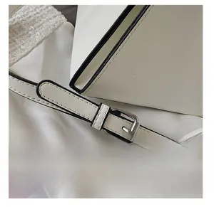 Détail de la bandoulière réglable en cuir blanc avec boucle argentée et bords noirs